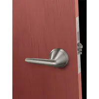 This passage lever lockset is constructed with cast stainless steel and a satin stainless steel finish. It is ligature-resistant and ADA compliant, with an ANSI F01 function for free egress without a key. Suitable for institutional settings requiring safety and corrosion resistance