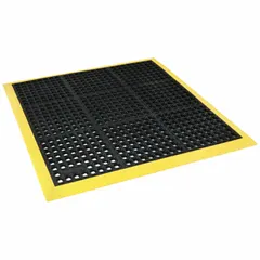 Rubber drainage mat with raised diamond studs, black with yellow border. 40 x 40 in, 7/8 in thick. Non-reversible. Suitable for wet or oily areas where slip resistance and standing comfort are needed.