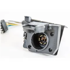 This trailer wiring adapter features a 7-Way blade configuration in a plastic housing. It is used to establish a standardized electrical connection between a towing vehicle and a trailer, supporting power and signal transfer for lighting, brakes, and auxiliary functions.