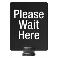 This black polyethylene sign displays a 'Please Wait Here' message for directing pedestrian flow. It measures 11 inches in length and 8 1/2 inches in width, and is designed for use with the Tempest Sign Stand. Commonly used in queue management applications in commercial or public spaces.
