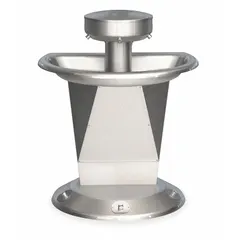This BRADLEY Sentry series wash fountain features a semi-circular stainless steel bowl with a central rising drain. It accommodates three users simultaneously via foot-operated push button controls, reducing hand contact. The unit measures 54 inches overall width and is finished in silver. It is not ADA compliant.