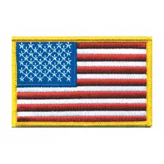This sew-on embroidered emblem features a gold U.S. flag design on a plastic base. It measures 3 1/2 inches by 2 1/4 inches and is attached by sewing onto fabric. Typical applications include uniform identification, morale display, or patriotic decoration on apparel, bags, or gear.