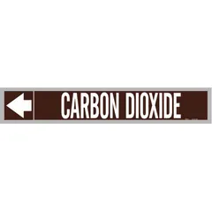 Brown adhesive pipe markers with white legend reading 'Carbon Dioxide' and directional arrows. Each roll contains 25 markers fitting pipe outer diameters from 2-1/2 to 6 inches. Used to identify pipes carrying carbon dioxide in industrial piping systems.