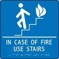 Adhesive sign with white/blue background and raised Braille text. Nominal size 9 in x 9 in. Mounts directly to walls or doors. Used to indicate emergency exit routes and instruct building occupants to use stairs instead of elevators during a fire