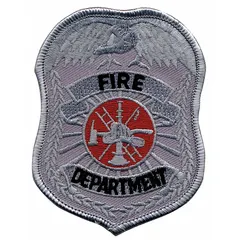 This embroidered badge measures 2 1/2 inches by 3 1/2 inches and is constructed from a polyester/rayon blend in a silver color. It is designed for attachment to uniforms, gear, or apparel to indicate department affiliation or role. Typical applications include fire department, security, or public safety identification.